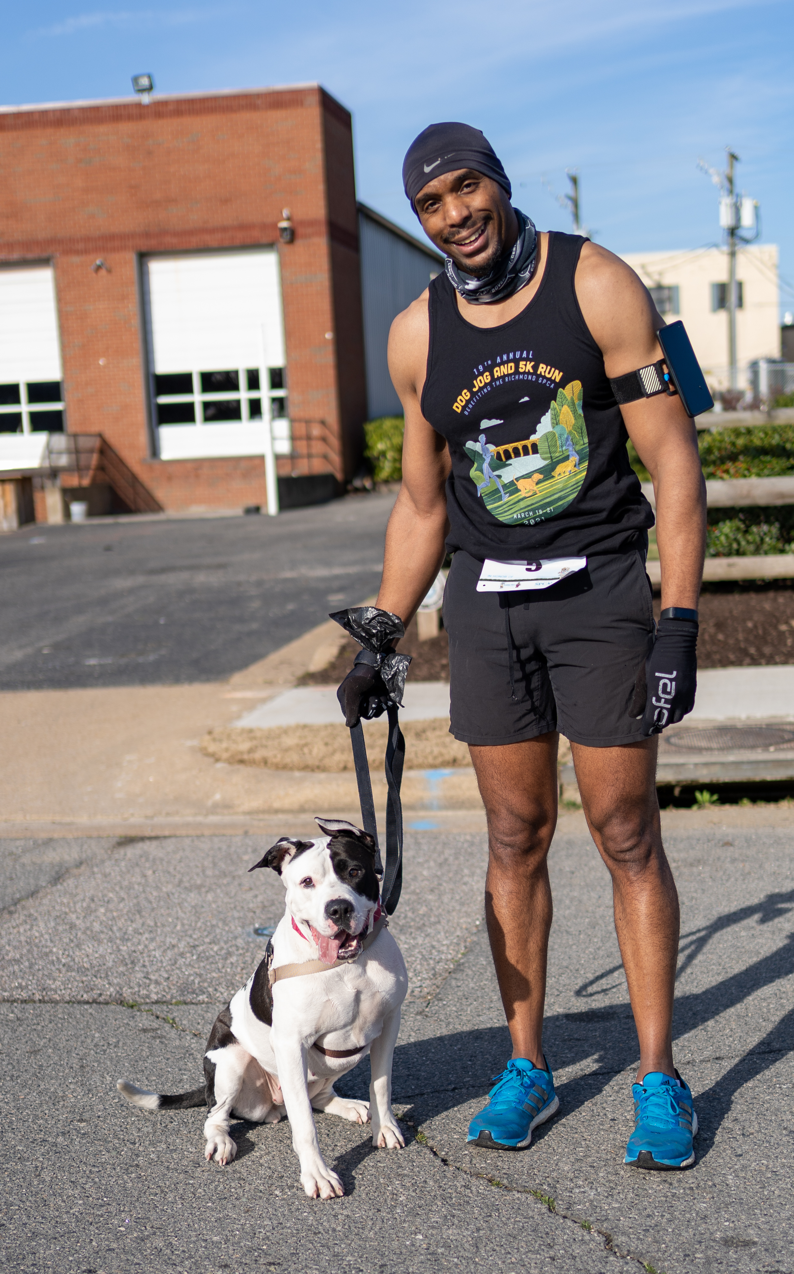 A runner wearing a Dog Jog and 5K Run tank top stands with a dog.