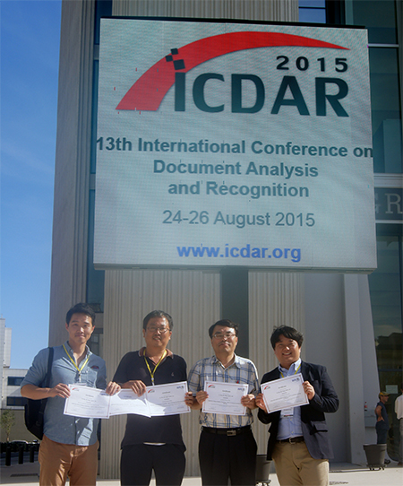 Four POSTECH-STRADVISION collaborators holding certificates beneath the ICDAR 2015 conference sign