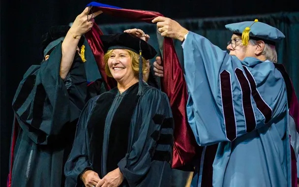 Bonnie Anderson smiling as she receives her honorary degree hood at IUP’s 2023 commencement