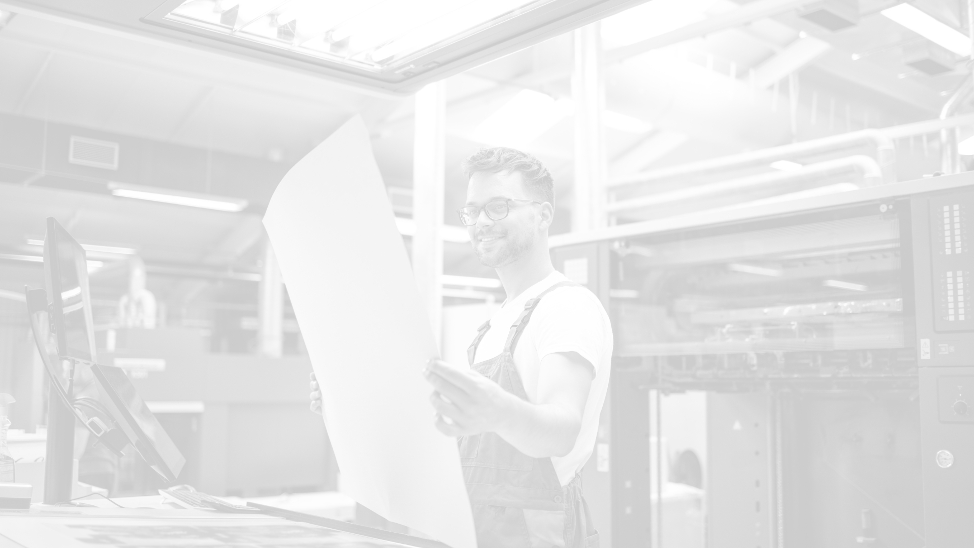 A print production worker inspecting a large printed sheet inside a pressroom