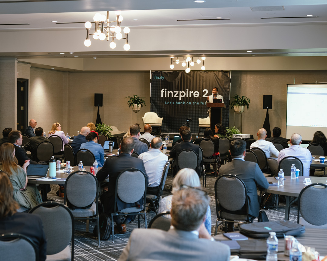 Booshan Rengachari speaking from a lectern to attendees at Finzly’s finzpire 2.0 conference