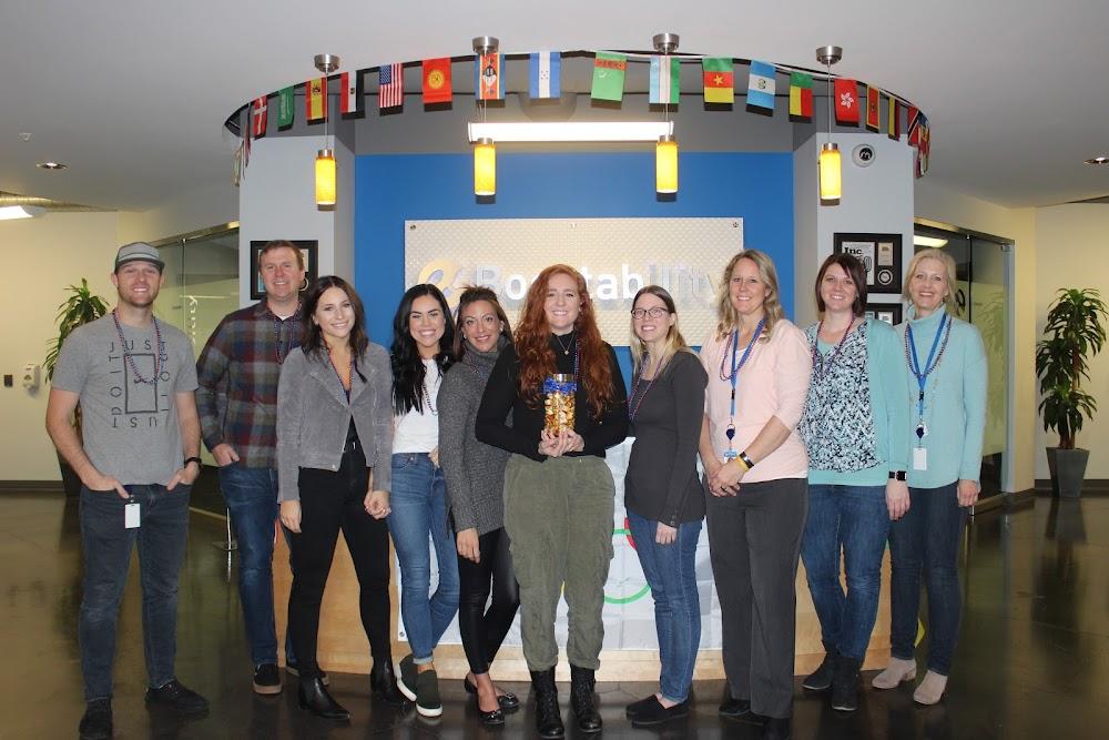 Boostability team members standing together in an office reception area beneath international flags