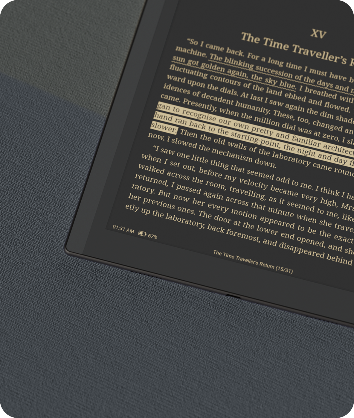 The Go 10.3 Lumi resting on grey fabric at night, its screen lit in warm amber showing a page of text