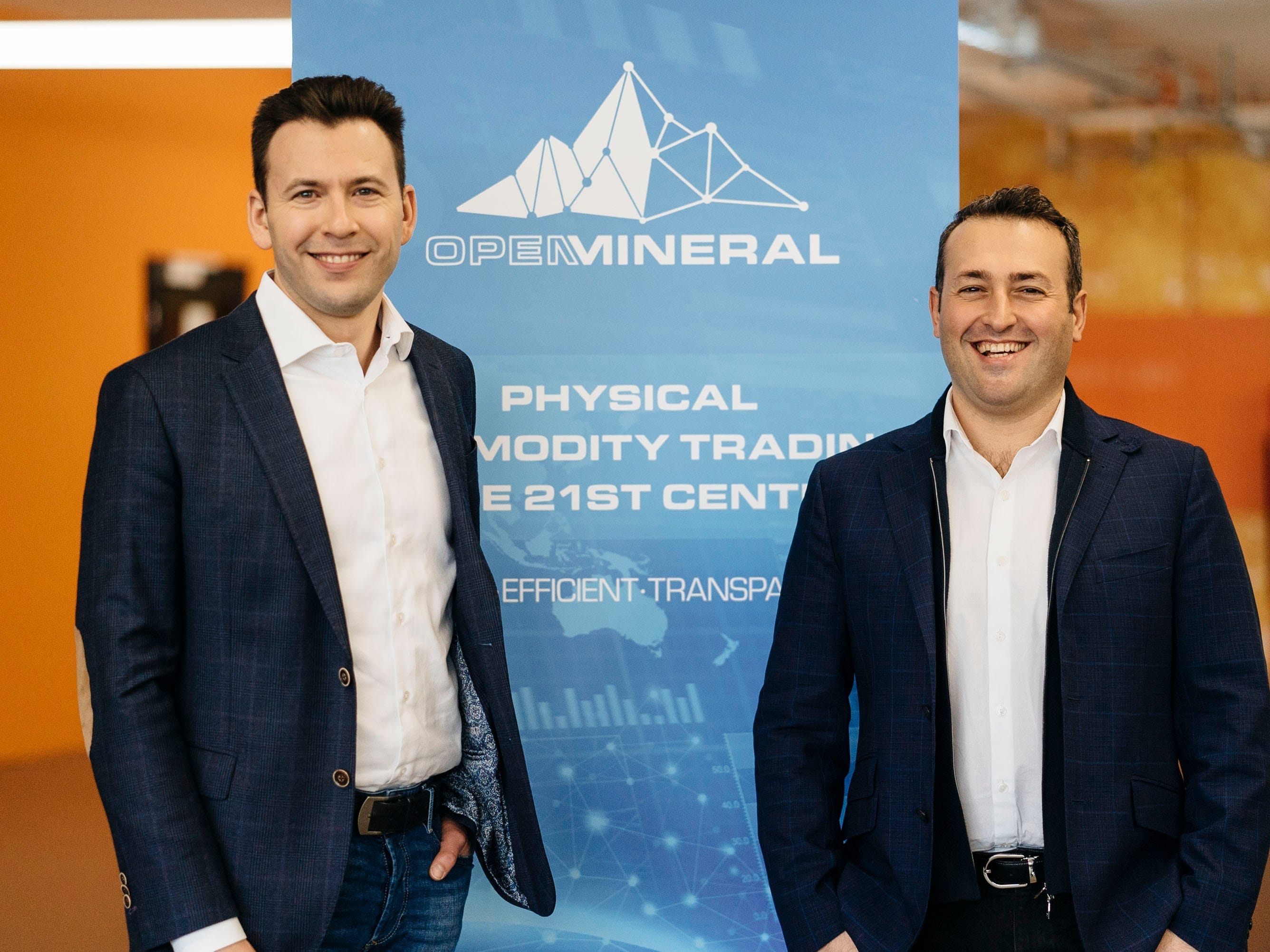 Open Mineral co-founders Ilya Chernilovskiy on the left and Boris Eykher on the right, standing beside a company banner