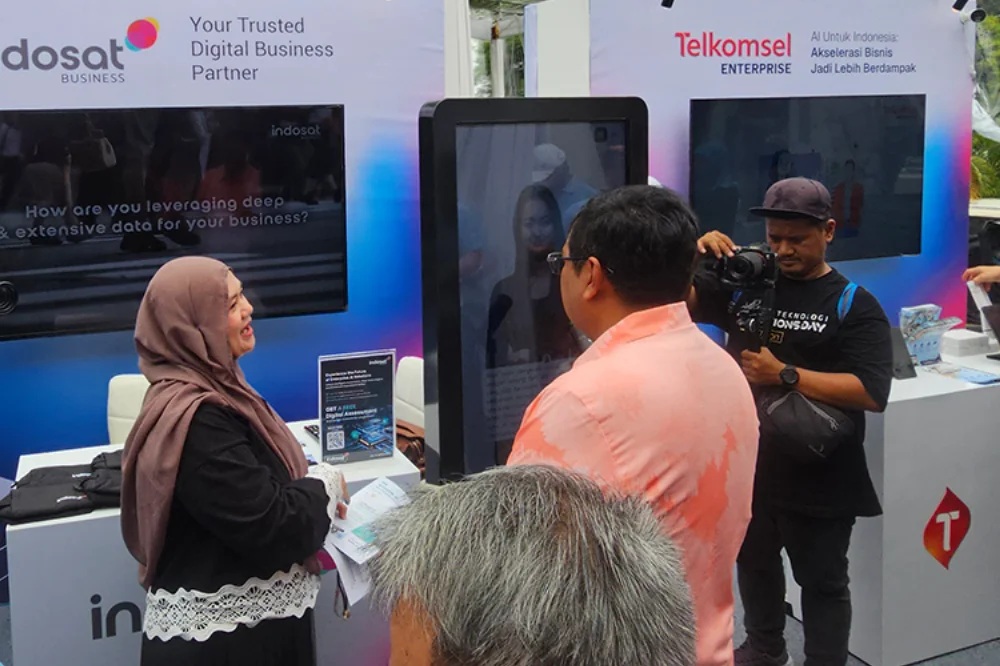 Visitors and a camera operator gathered around a digital human kiosk at Lintas Teknologi Solutions Day 2025