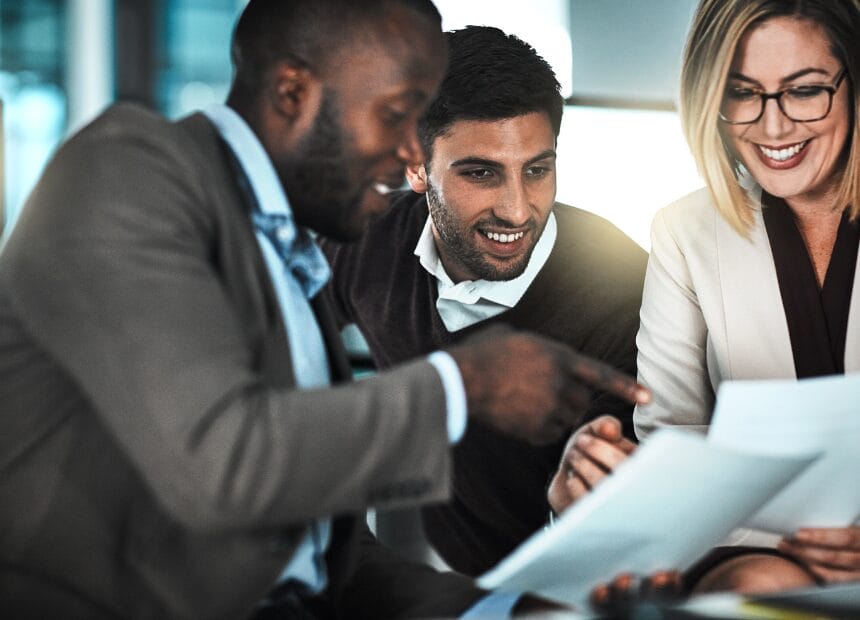 Three colleagues reviewing documents together in an illustrative workplace photograph
