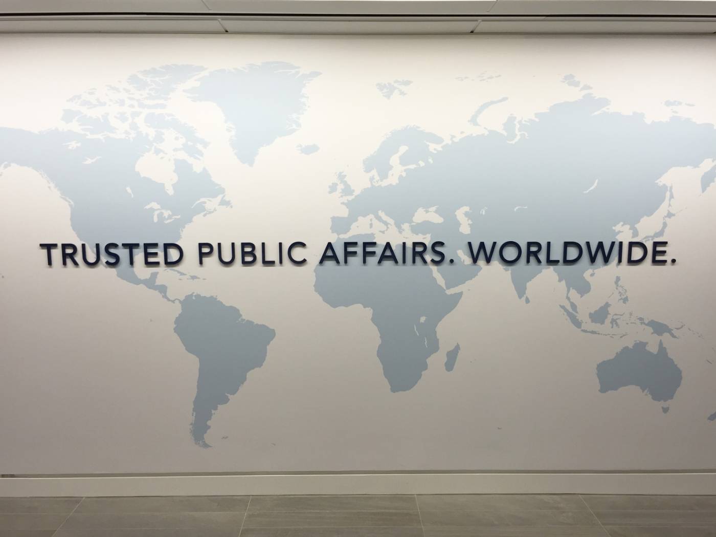 A world map and the words Trusted Public Affairs, Worldwide on a DDC office wall