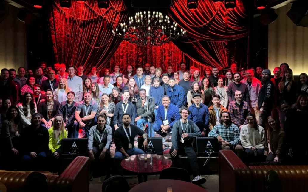 Kustomer team members gathered together on a stage beneath red curtains and a chandelier