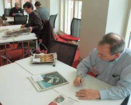 Brad Buchanan in the foreground reviewing newspaper advertising entries, with other judges behind him