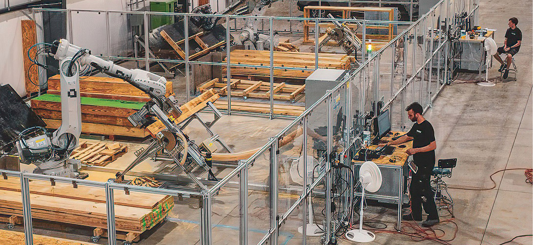 Operators working beside a robotic arm handling timber at Rival Lab