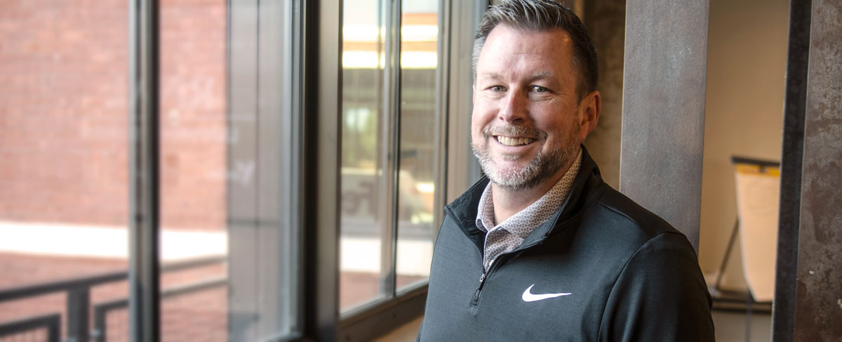 Brad Crawford smiling beside large windows