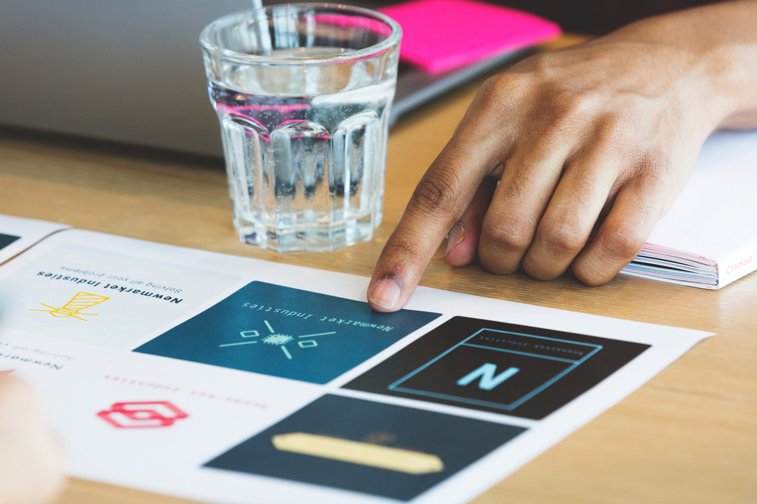 Hands arranging printed design options around a work table