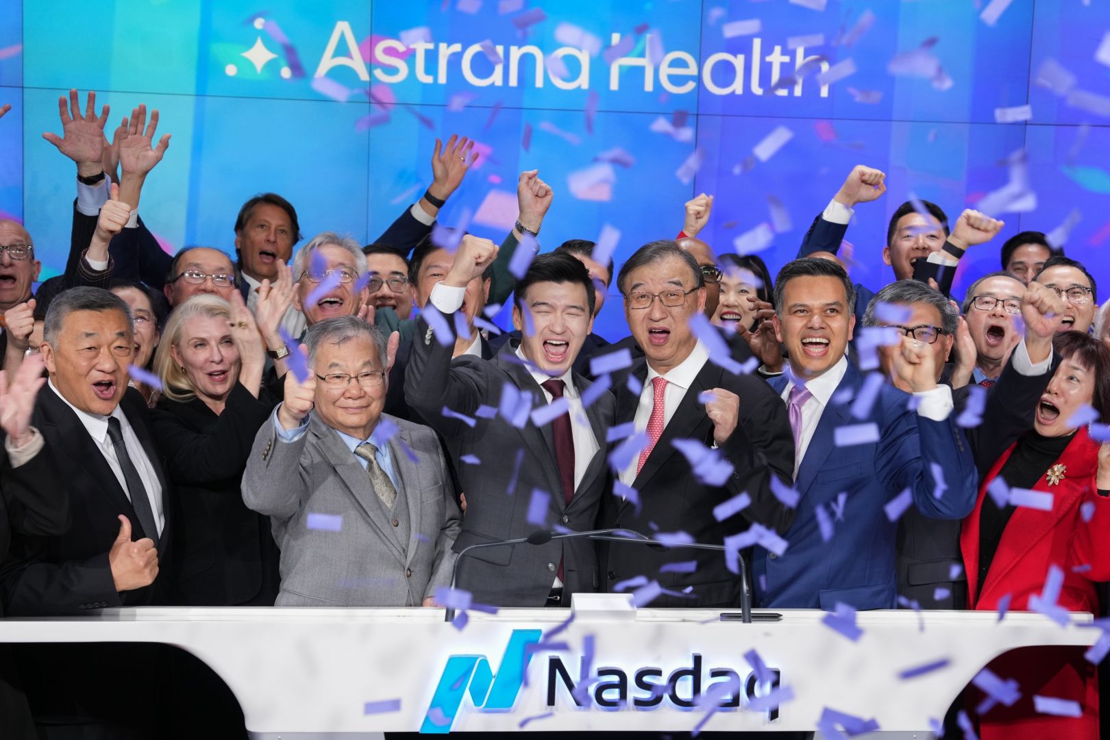 Brandon Sim and Astrana colleagues celebrating at the Nasdaq podium beneath falling confetti