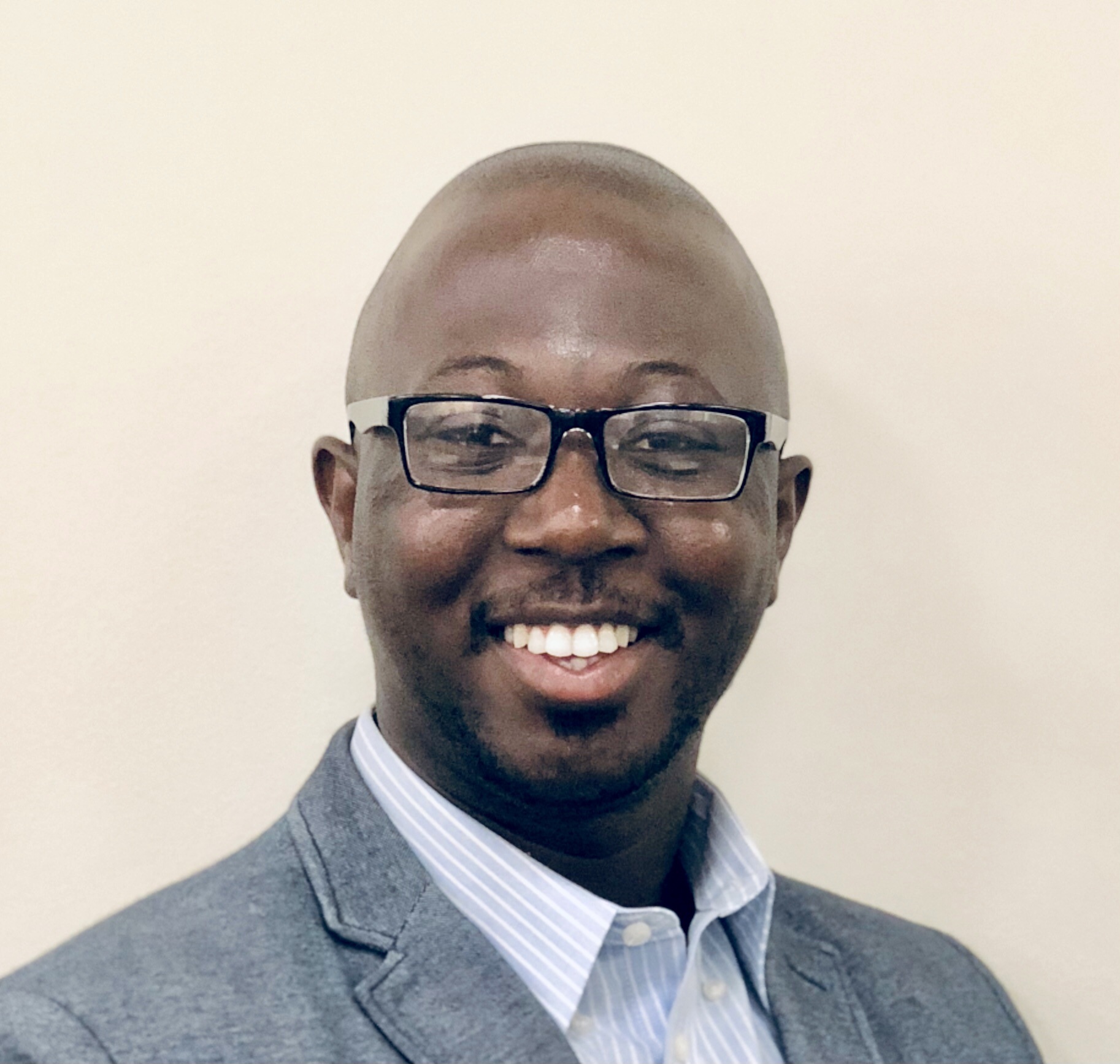 Bravely coach Adewale Bello smiling in glasses and a jacket