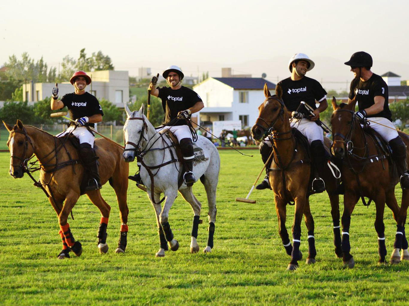 Four riders wearing Toptal shirts playing polo in Argentina