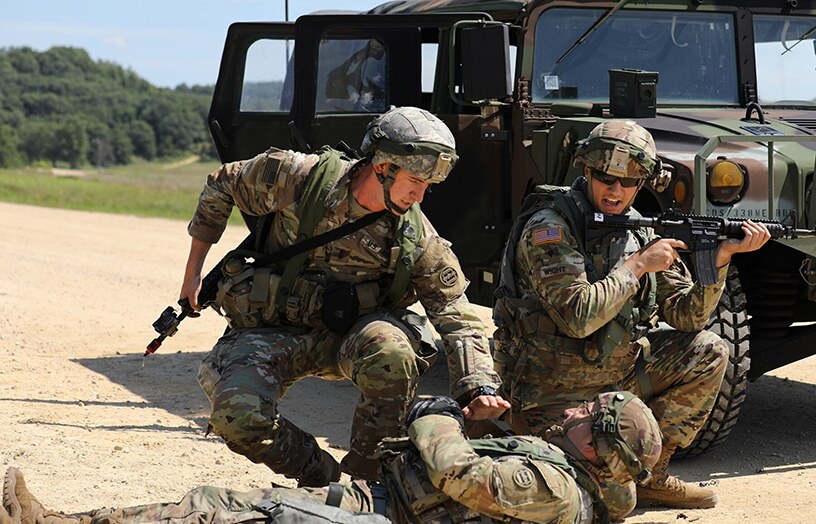 Military personnel working beside a field vehicle during a training exercise