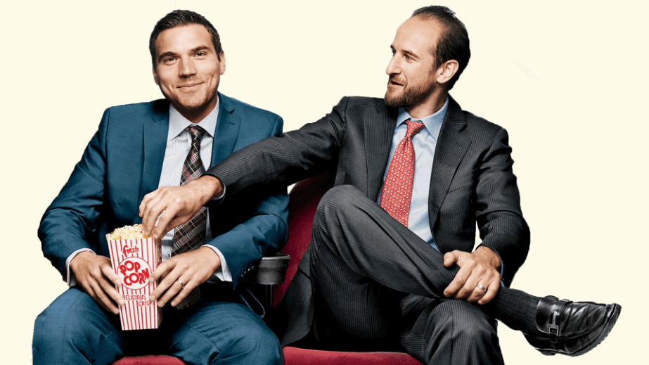 Chris O’Brien, left, and Brett Goldberg, right, seated together as Goldberg reaches for popcorn