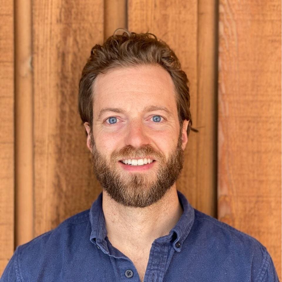 Brett Shaheen in a blue shirt, photographed against a wooden backdrop