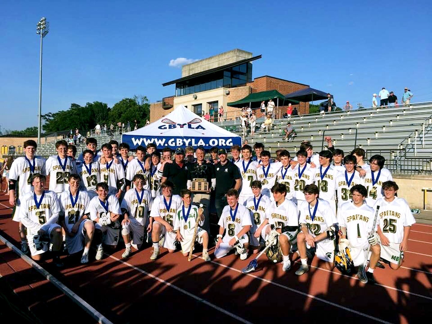 Mountain Brook High School boys lacrosse players and coaches celebrate their 2018 championship on the field