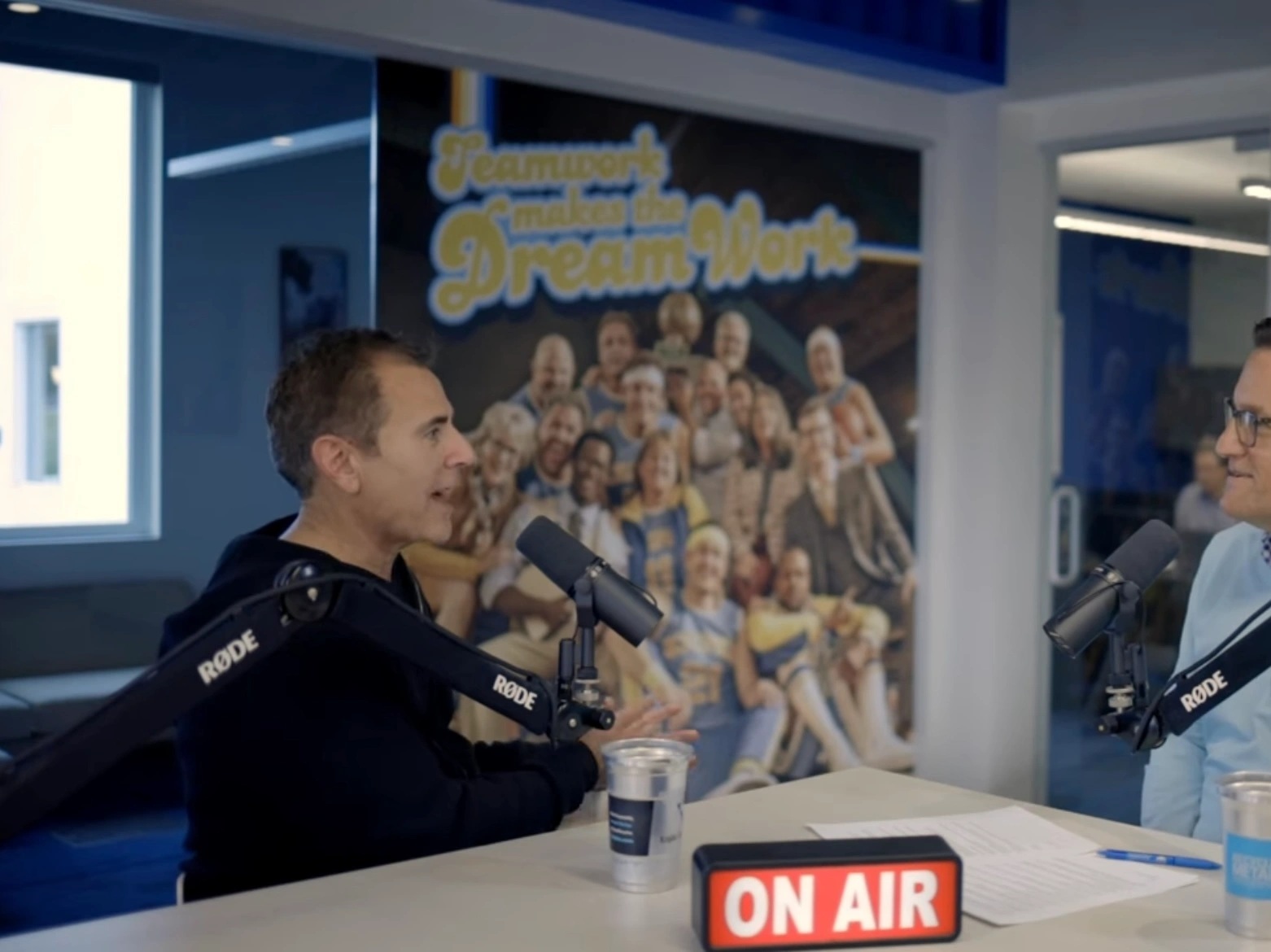 Brian Elias, at left, speaking into a microphone during an interview