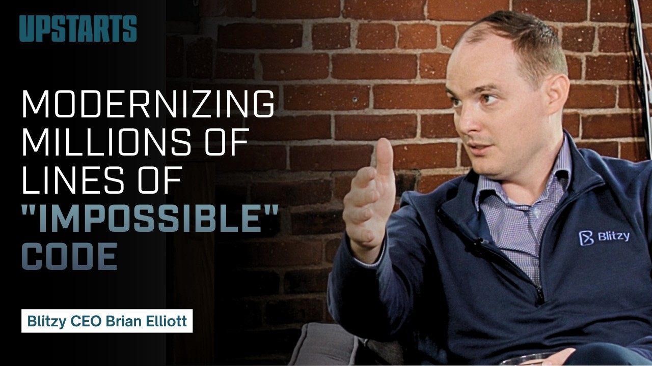 Brian Elliott gesturing during his Upstarts Podcast interview, seated against a brick wall