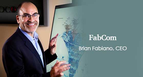 Brian Fabiano smiling beside a display in a FabCom press photograph