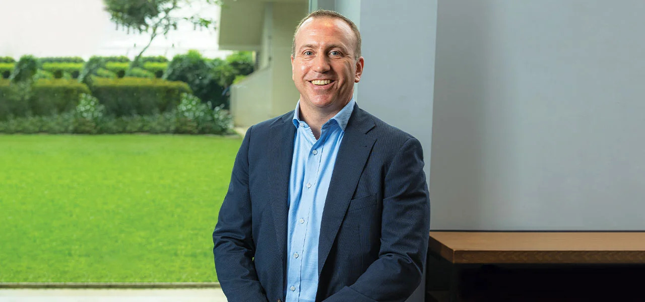 Brian Jochum seated in a bright office beside a green courtyard