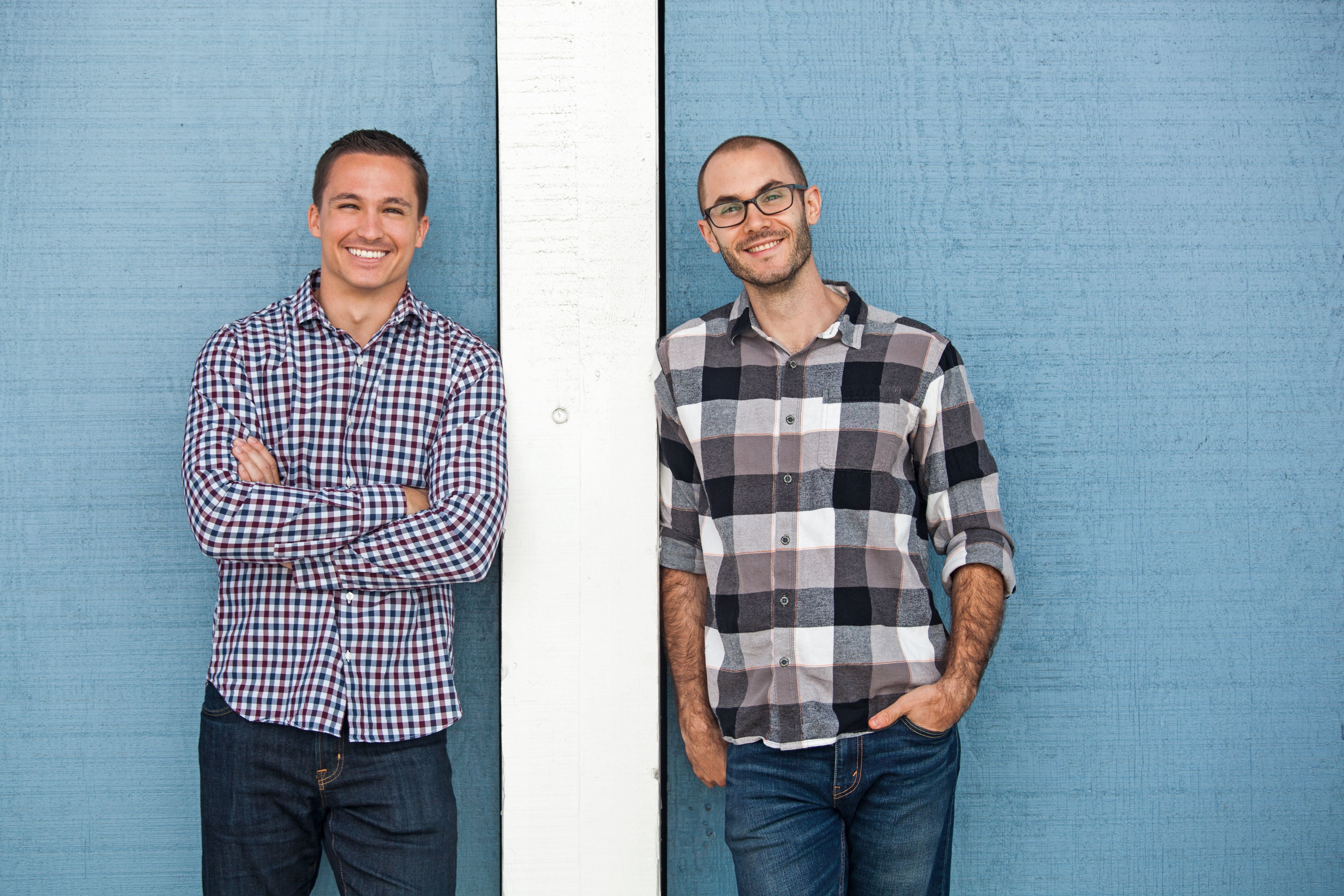 Brian Kidwell, left, and Scott Keyes, right, standing together in front of a blue wall