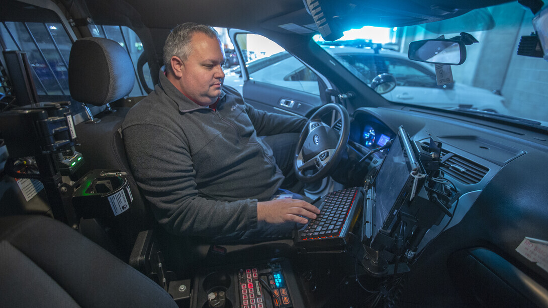 A campus public-safety technology specialist examines a computer mounted inside a patrol vehicle
