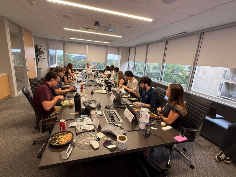 Brian Lane at the far end of a conference table during lunch with employees