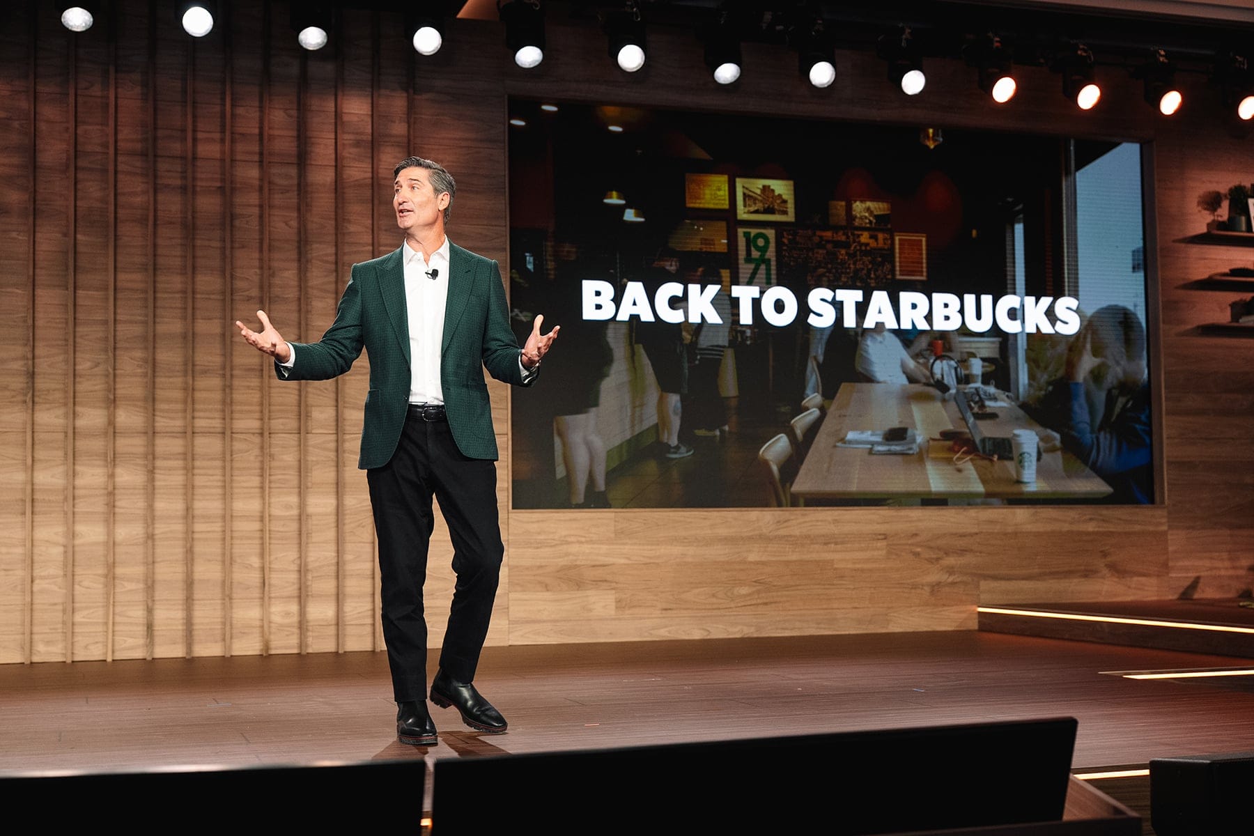 Brian Niccol speaking onstage beside a Back to Starbucks presentation at Investor Day in January 2026