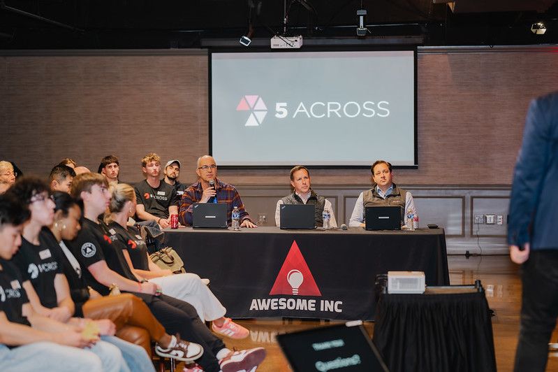 Judges seated behind an Awesome Inc table at a 5 Across event