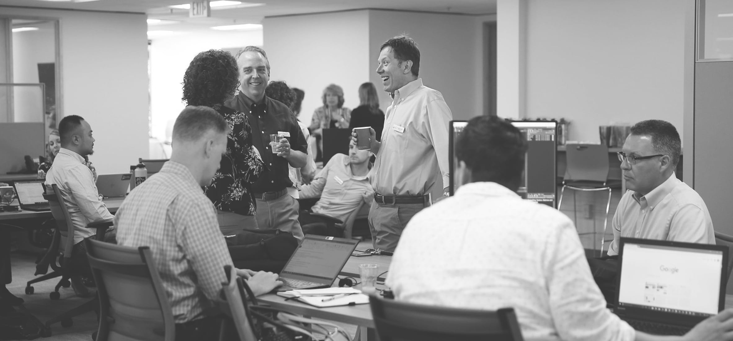 Bridge colleagues gathering among desks and laptops in an open office