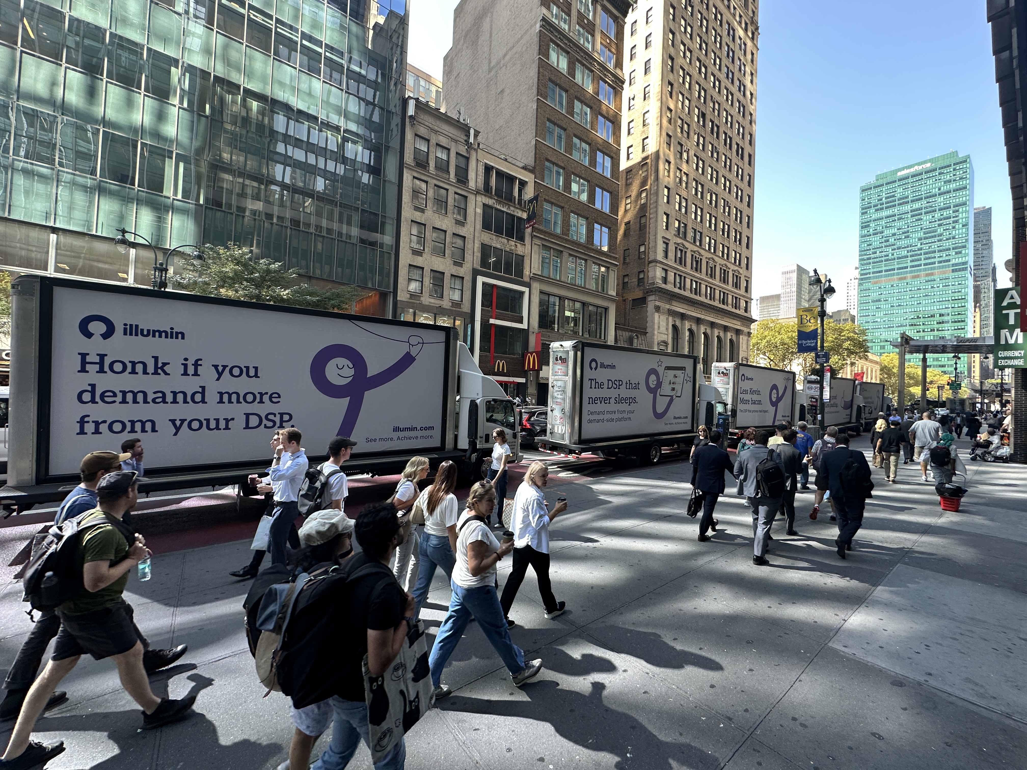 A line of illumin mobile billboards moving through a busy New York street during Advertising Week