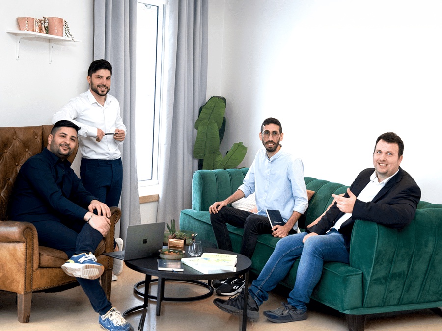 BridgeWise founders Dor Eligula, Or Eligula, Mor Hazan and Gaby Diamant seated and standing in an office