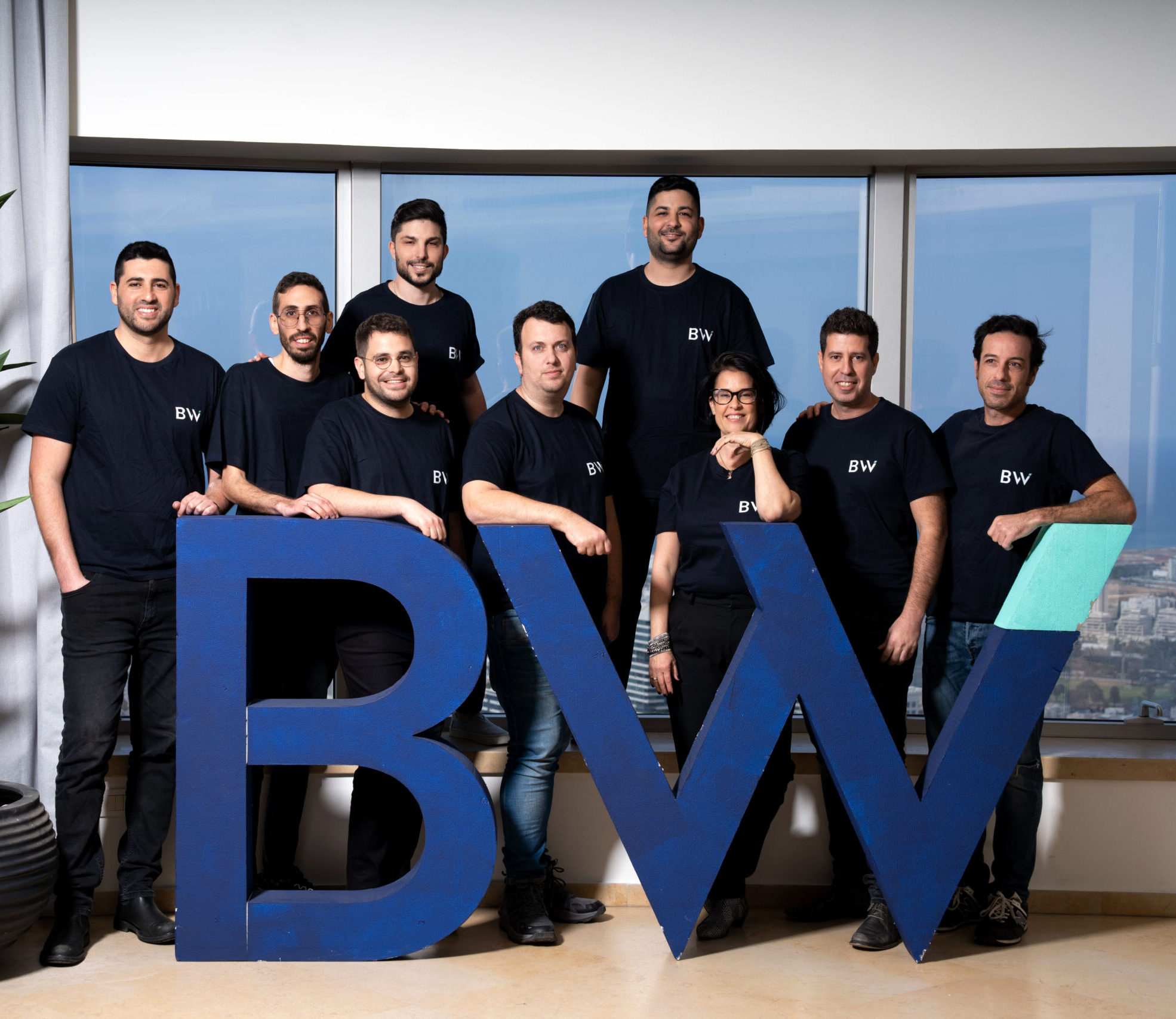 BridgeWise team posing behind large blue BW letters