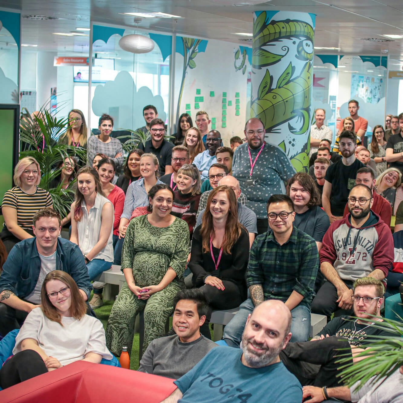 A large group of BrightHR employees gathered in a colourful Manchester office