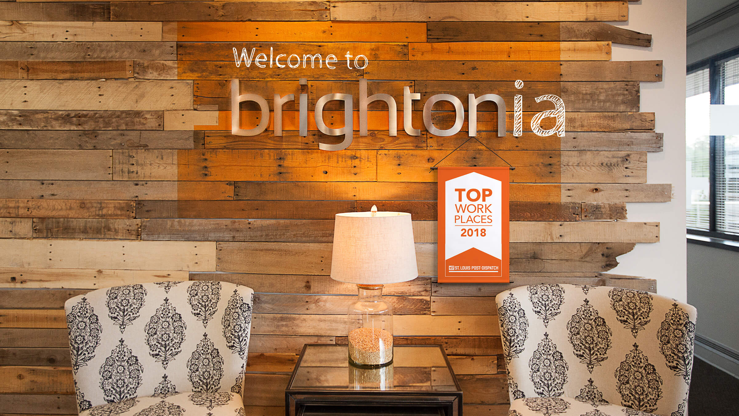 Brighton Agency's office lobby with a reclaimed wood wall and Brightonia sign