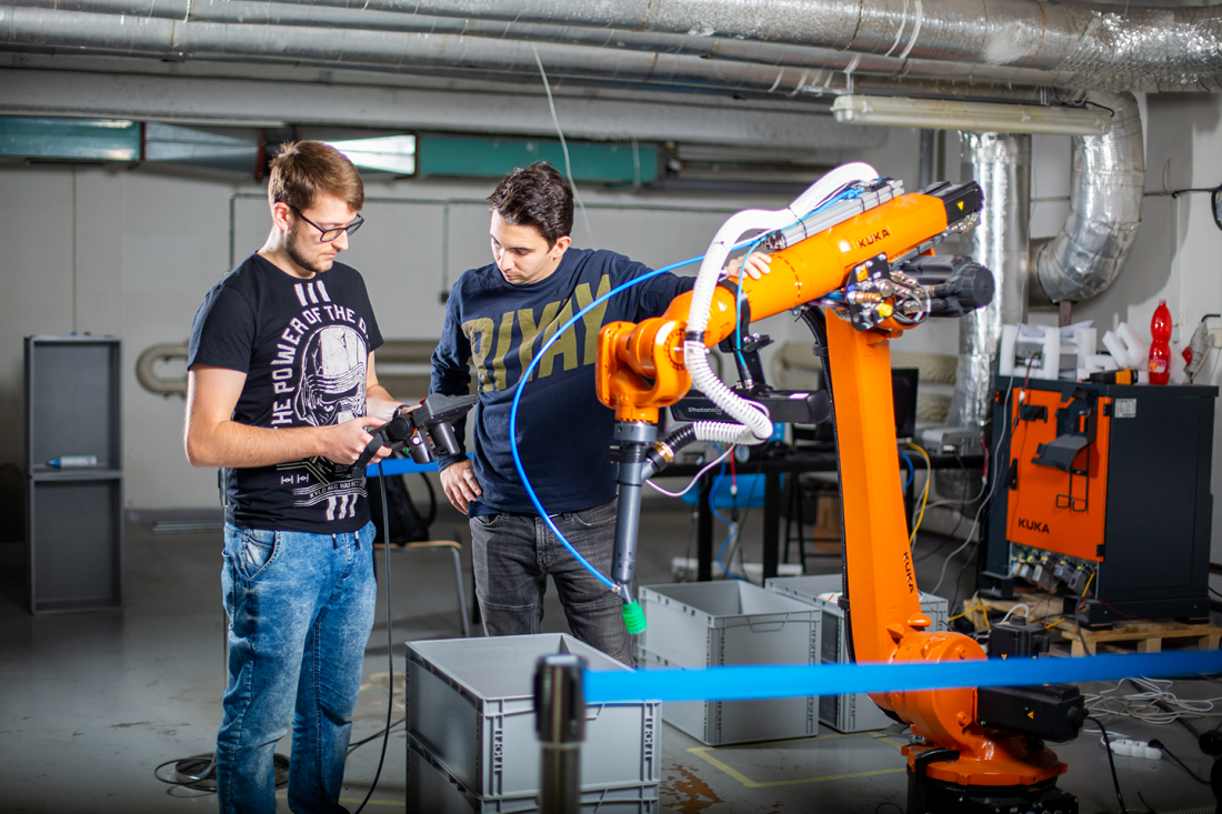 Two team members working with a robotic arm in a laboratory