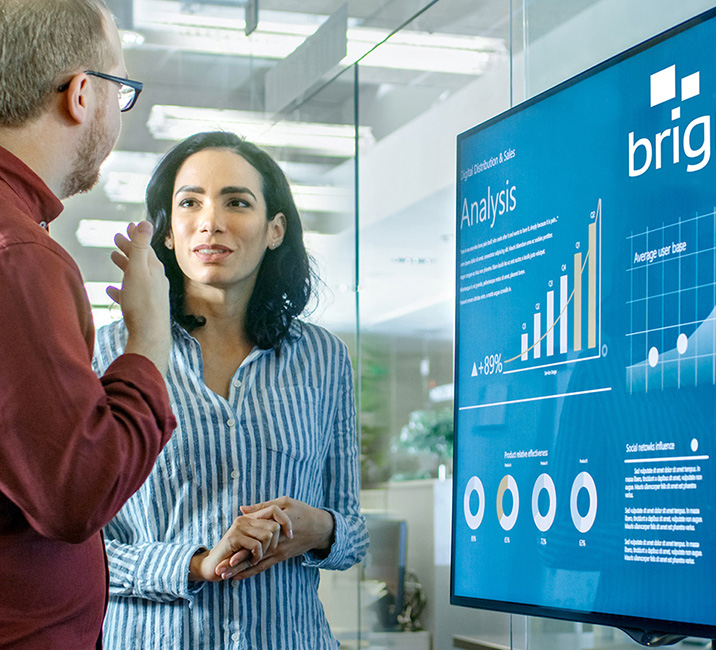 Brightree promotional photograph showing professionals reviewing software analytics on a large display