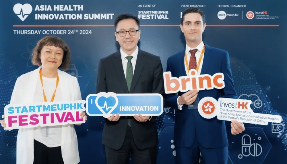 Participants holding event signs at the Asia Health Innovation Summit, including a Brinc sign