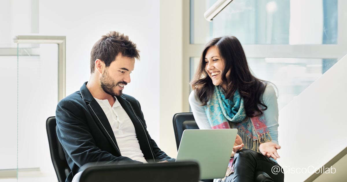Two people talking beside a laptop in a Cisco collaboration marketing photograph.