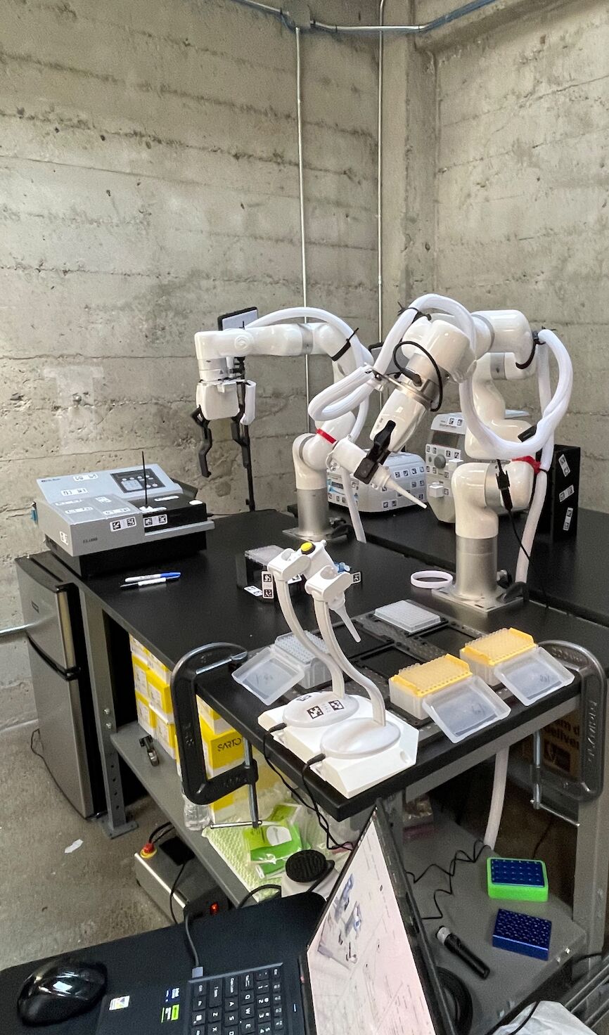 Two robotic arms, cameras, laboratory equipment and plates on Zeon’s workbench
