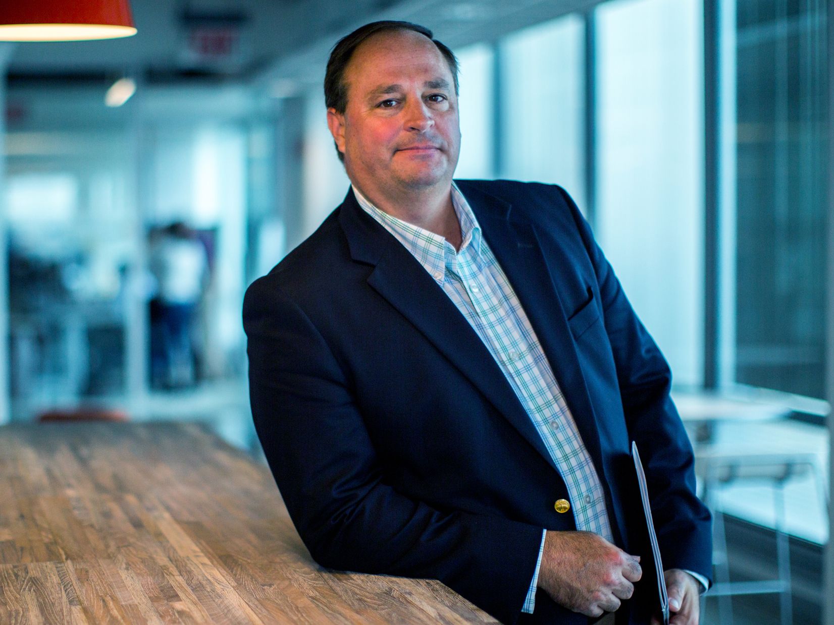 Brooks Tingle leaning against a table in a window-lined office