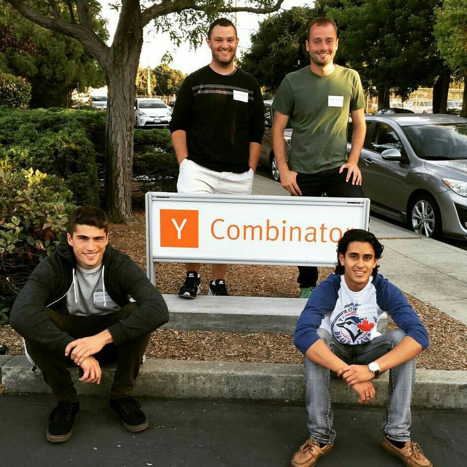 The four early PartnerStack founders gathered around a Y Combinator sign