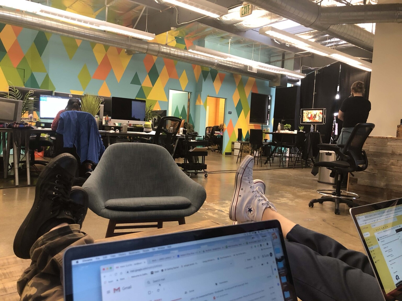 An informal studio photograph showing desks, colorful geometric walls and a shooting area