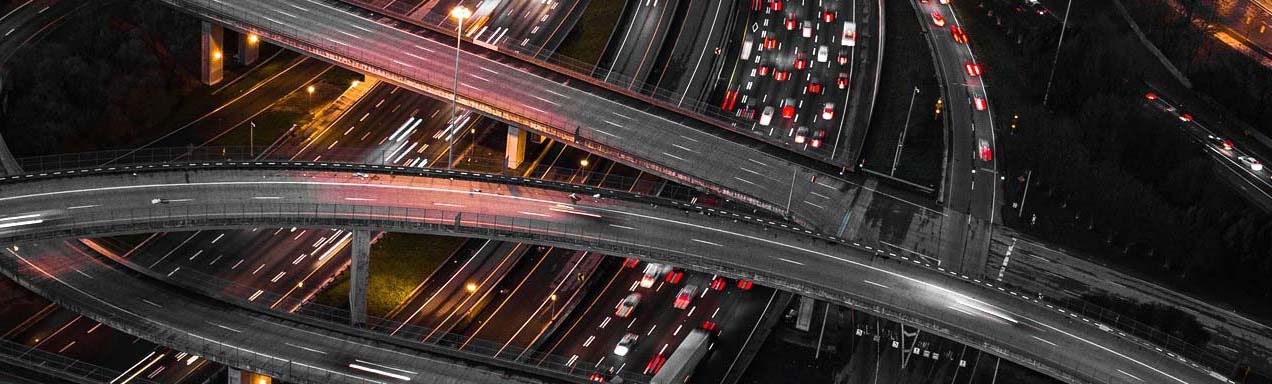 Aerial night view of a multi-level highway interchange with streaking traffic