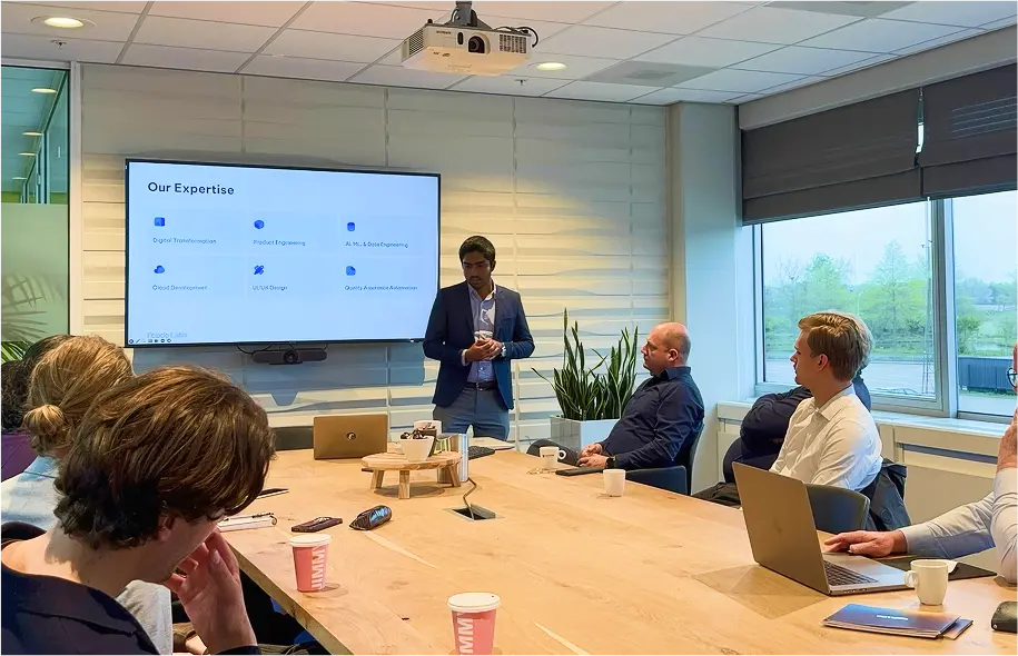 Buddhishan Manamperi presenting Fcode Labs’ services to people seated around a meeting table