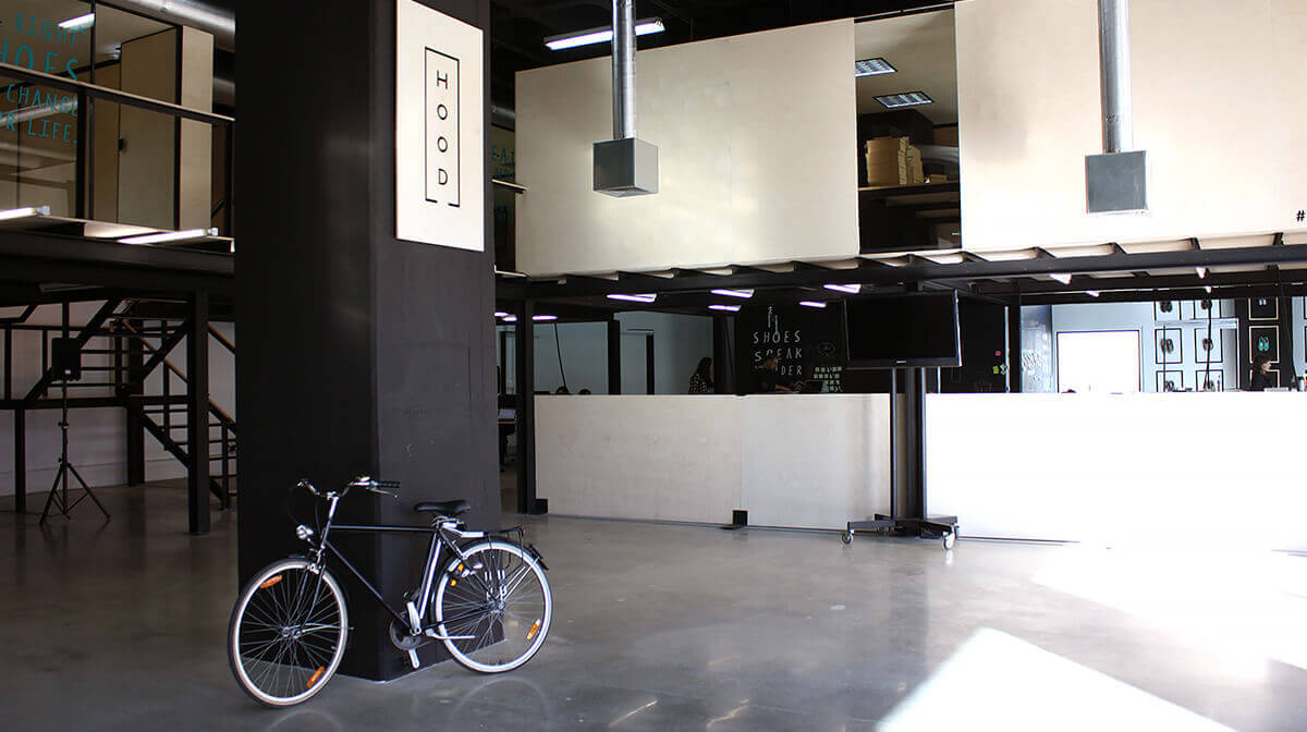 The HOOD coworking interior used by Build Up Labs, with mezzanine workspaces and a bicycle