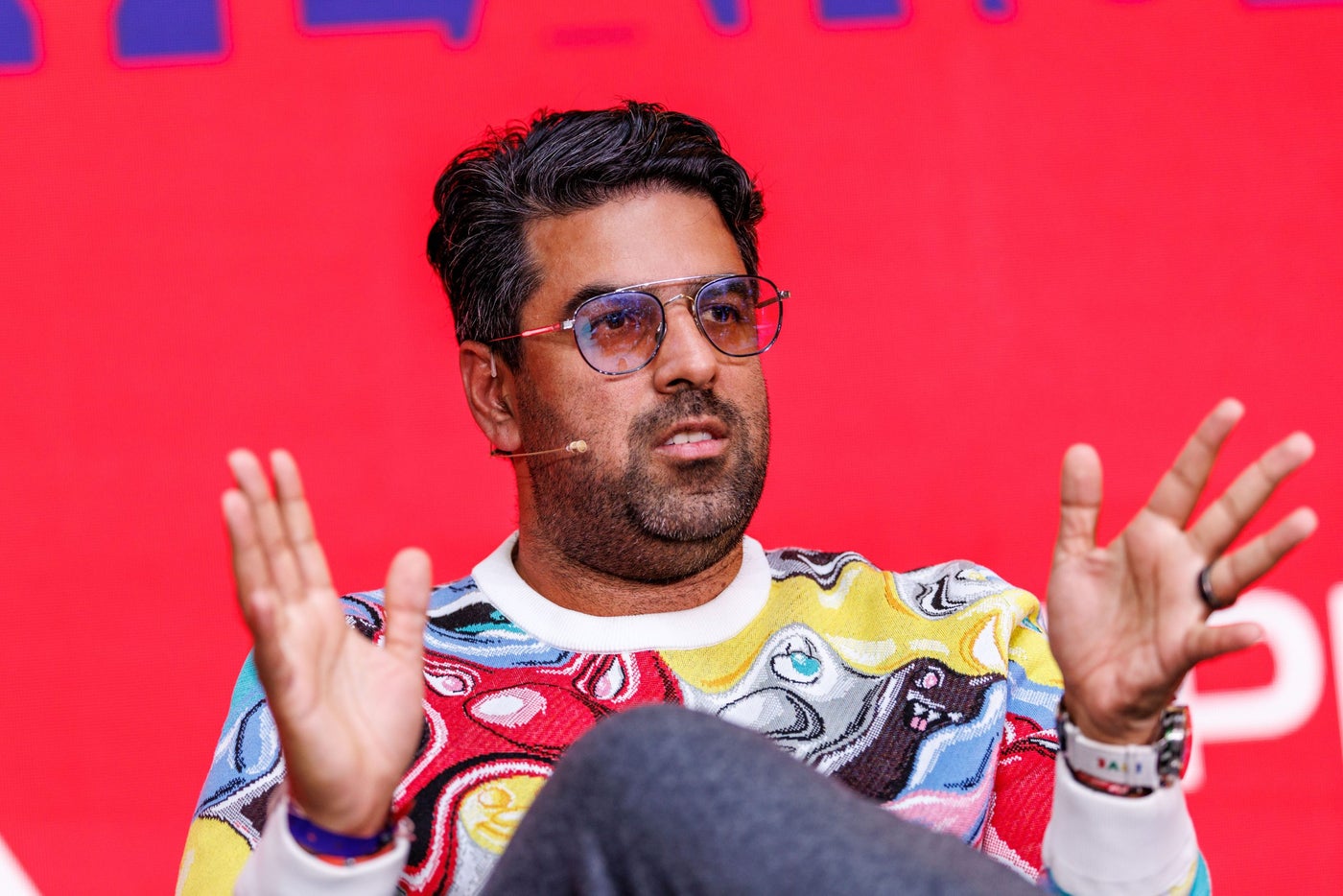 Builder.ai founder Sachin Dev Duggal speaking onstage in a patterned sweater